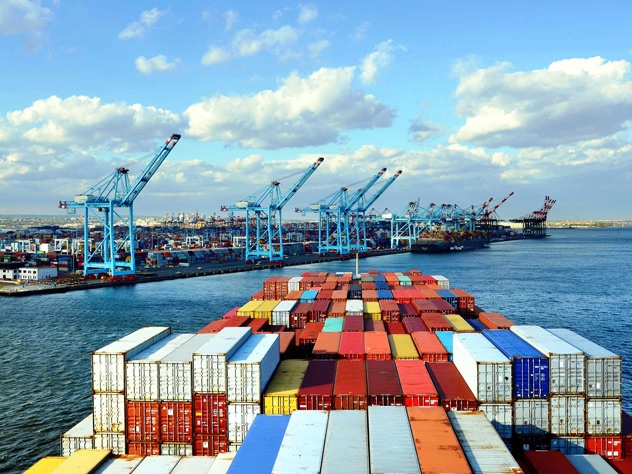 Container ship full of containers in front of harbour cranes