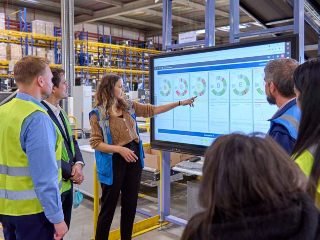 a woman in a warehouse explaining analytics on a screen